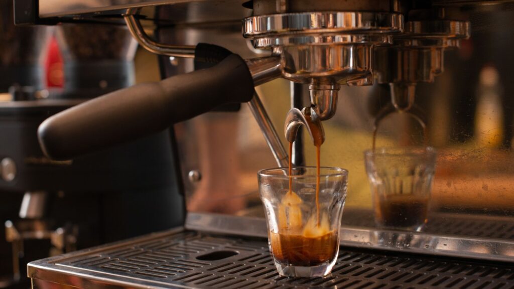 Nespresso machine brewing rich, high-quality espresso into a clear glass cup in a buzzing coffeehouse.