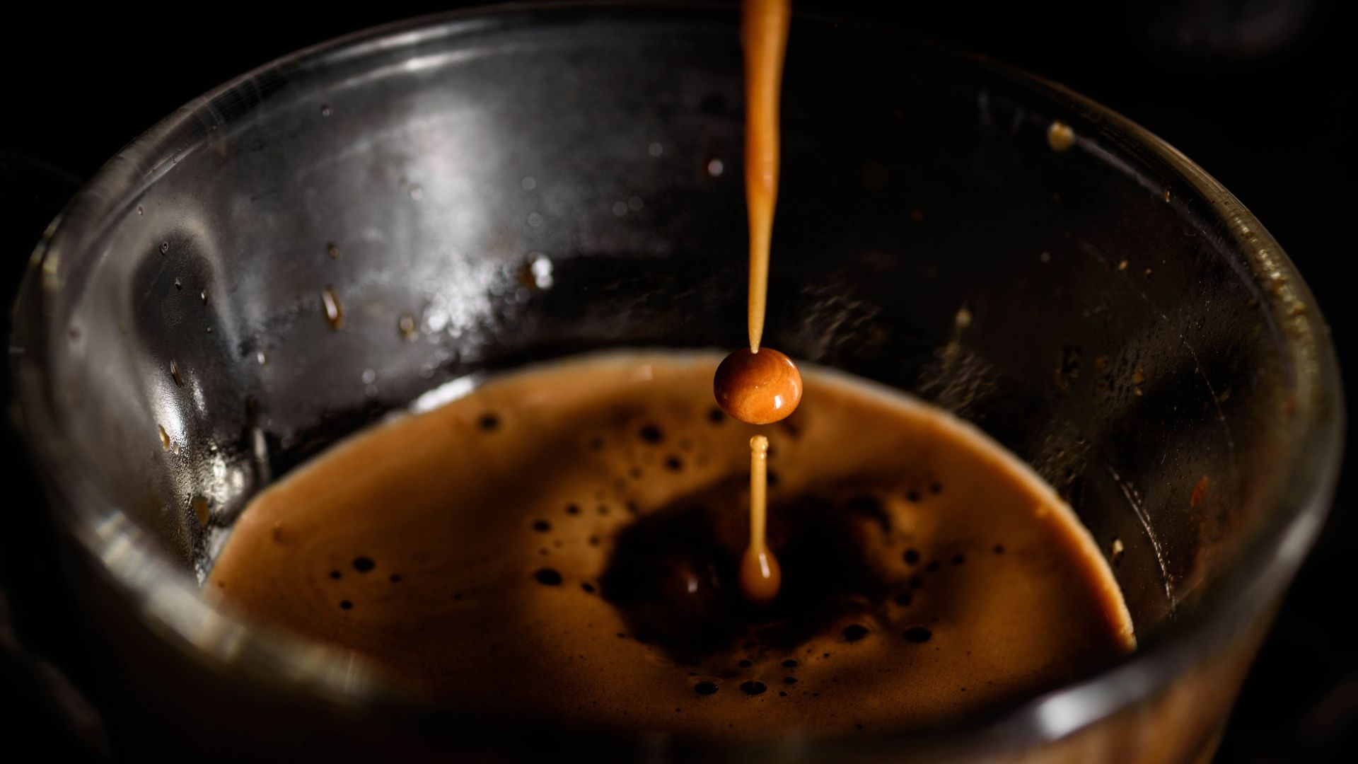 Pouring espresso into a glass cup, capturing the rich color and creamy texture of freshly brewed coffee.