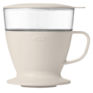 OXO Brew coffee maker, a multi-purpose kitchen tool with a clear measuring cup and light beige base.