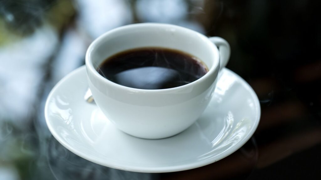 Simple coffee cup setup with fresh, dark brew in a white ceramic cup and saucer.